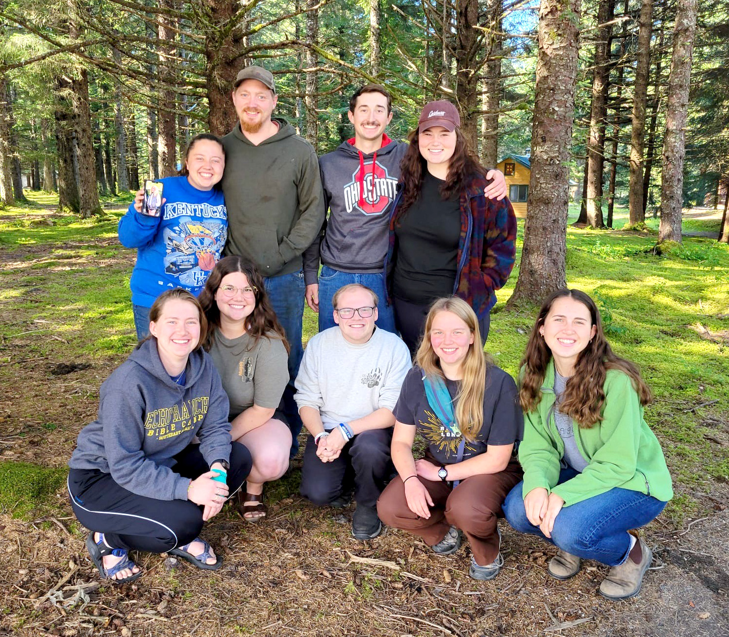 Immersion 15 participants serving at Echo Ranch in Alaska pause for a group photo among the camp's evergreen trees, celebrating a summer of ministry, work projects, and community living.